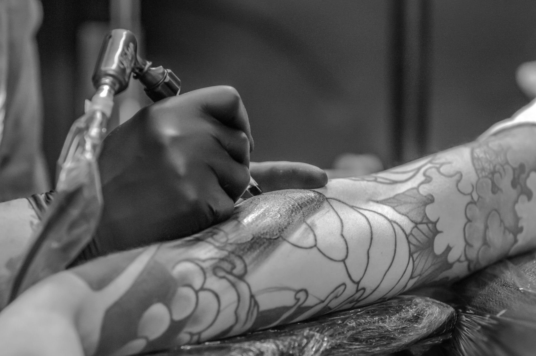 Tattoo artist creating a detailed black and grey tattoo