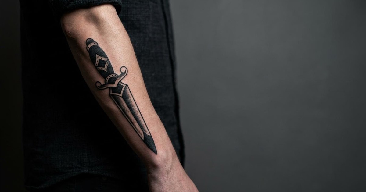 Traditional dagger tattoo on a forearm with the blade pointing down